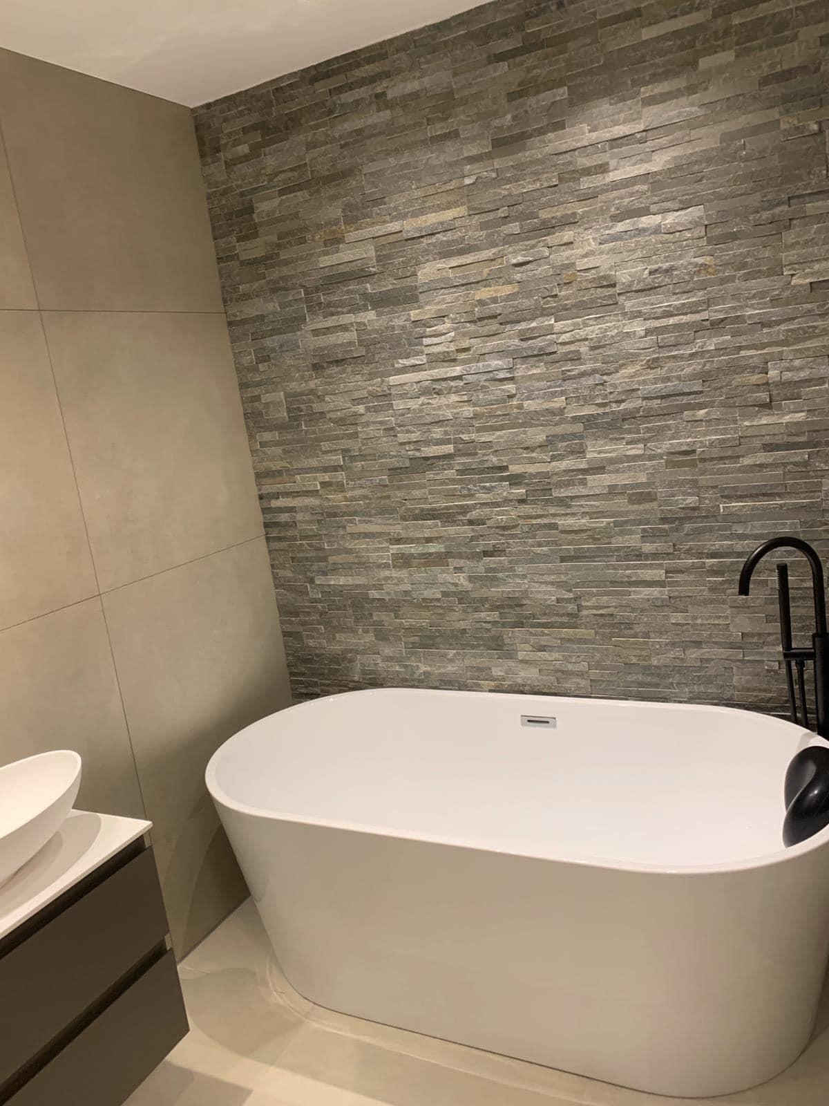 Vrijstaand bad in moderne badkamer met natuursteen wand